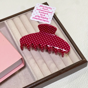 Detailed view of large red polka dot hair claw clip on a velvet display tray