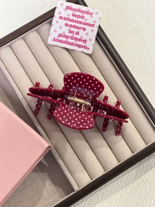 Detailed view of dark red polka dot hair claw clip with golden metal spring