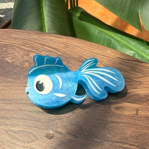 Pince à cheveux élégante en acétate forme poisson bleu sur fond en bois naturel