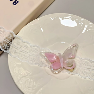 Macro view of pink butterfly hair clip with pearlescent finish on a vintage plate