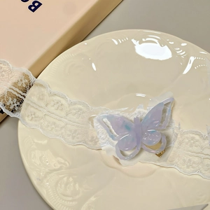 Detailed view of lavender butterfly hair clip with white lace ribbon on ceramic plate