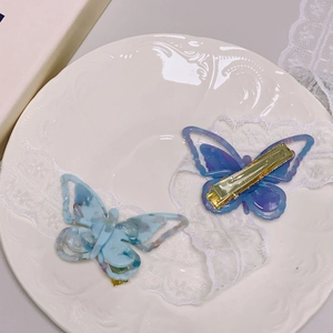 Detailed close-up of acetate butterfly hair clips with elegant marble patterns and gold metal clips