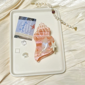 Pink ocean seashell hair claw clip with starfish detail on elegant silk background