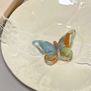 Elegant butterfly-shaped acetate hair clip with colorful marble effect on porcelain