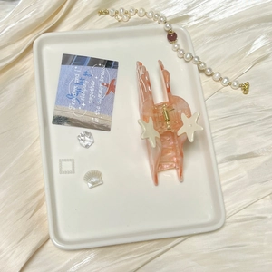 Detail of pink marble textured starfish hair claw clip on elegant beige satin backdrop