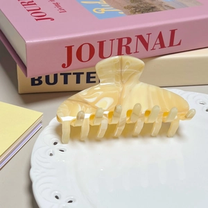 Elegant cream marbled acetate hair claw clip shown on a ceramic plate for styling