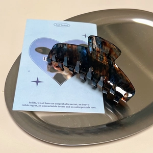 Minimalistische Haarklammer aus Acetat mit braunem Schildpattmuster auf Metalltablett