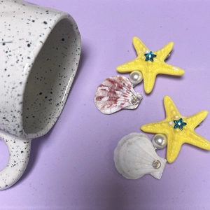 Détail de pinces à cheveux avec étoile de mer, coquillage et perle sur fond violet