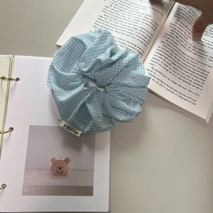 Schickes blau-weiß kariertes Baumwoll-Haargummi auf Vintage-Büchern für Pferdeschwänze