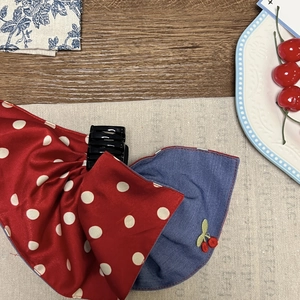 Detailed shot of fabric claw clip with red polka dots and denim cherry embroidery