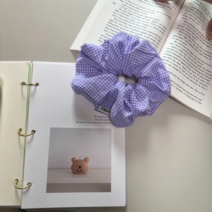 Klassisches lila kariertes Haargummi mit Stoffstruktur auf Buch für das tägliche Styling