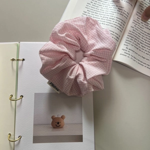 Haargummi mit rosa Karomuster aus Baumwolle und Markenetikett auf Buch-Hintergrund