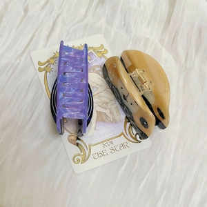 Detail view of purple marble and beige bear acetate hair claws on white silk background