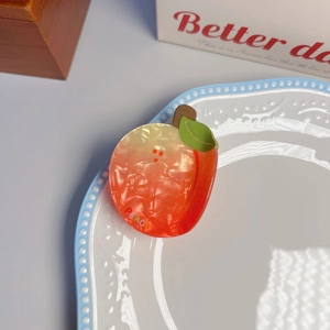 Close-up of marble pattern acetate peach claw clip with green leaf and PEACH text logo