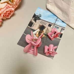 Detailed view of pink petal-shaped mini hair claws with glossy resin finish and gold springs