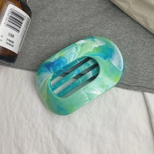 Détail d'une grande pince à cheveux ovale avec texture acétate marbrée bleu-vert