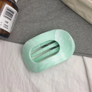 Détail d'une pince à cheveux en acrylique vert menthe à motif marbré avec structure ovale
