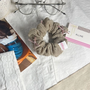 Gros plan d'un chouchou beige avec nœuds roses et étiquettes sur tissu blanc plissé