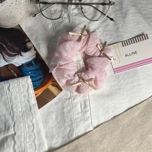 Chouchou en résille rose avec nœuds dorés sur une chemise blanche, style lifestyle
