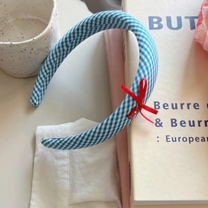 Blue gingham check headband with a red LOVE bow detail for women in a lifestyle setting