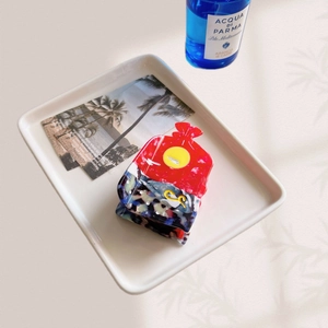 Detail of red and floral acetate sea creature hair claw clip on a beach tray