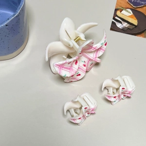 Detailed macro view of cream mini hair claws with pink checkers and cherry patterns