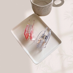 Detail view of red and blue translucent acrylic hair claws on a ceramic plate