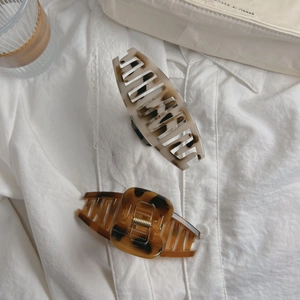 Elegant tortoiseshell claw clips in cream and amber on white lace blouse fabric