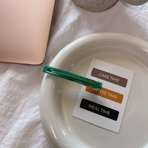 Elegant emerald green transparent hair clip with golden handmade lettering on a plate