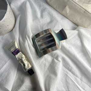 Detail of matte perfume bottle hair claw clip with marble texture on white linen cloth