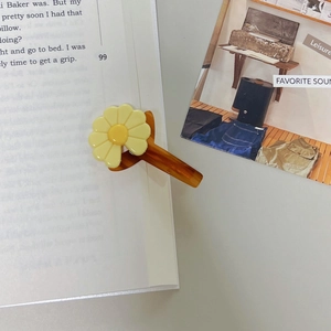 Detailed shot of yellow daisy flower hair clip on tortoise shell resin clip with magazine