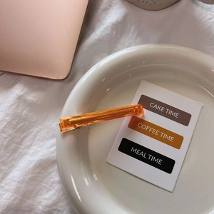Elegant orange clear acetate hair clip with gold handmade text in a ceramic dish