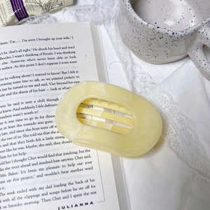 Elegant pale yellow marbled hair claw clip on an open book with a ceramic mug