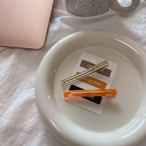 Detail of elegant gold metal clip and translucent amber acetate hairpins on white tray