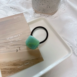 Elegant green acrylic square hair tie on white ceramic tray with minimalist chic style