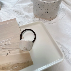Detail of white square resin charm with gold France Handmade text on black hair tie