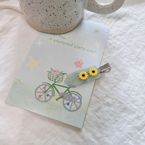 Floral duckbill hair clip with daisy design on light blue base and cotton backdrop