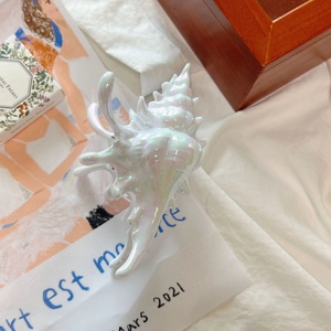 Détail de la pince à cheveux en forme de coquillage blanc aurora avec finition irisée