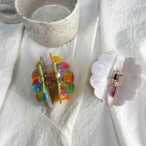 Detail of colorful marble acetate hair claw and white shell hair clip with pearls