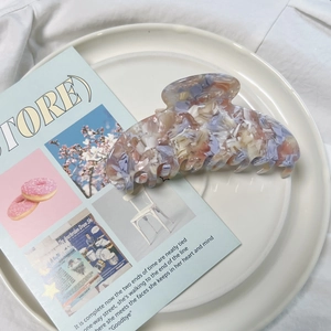 Grande pince à cheveux élégante en acétate avec texture de galets colorés sur une assiette