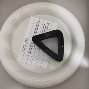 Detail of a minimalist black hollow triangular hair claw clip with glossy finish and metal spring