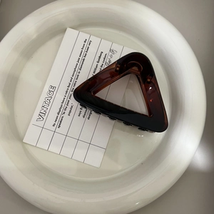 Detailed top view of a dark amber triangle hair claw clip with glossy finish on white tray