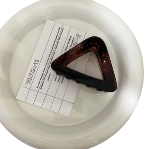 Elegant amber triangular hair claw clip with vintage butterfly design on white ceramic plate