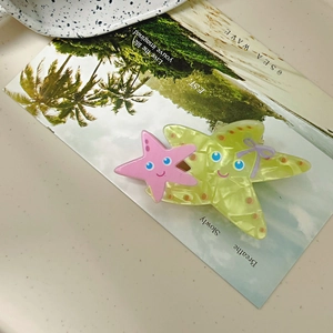 Detail of acrylic starfish hair claw with neon green starfish and purple bow decoration