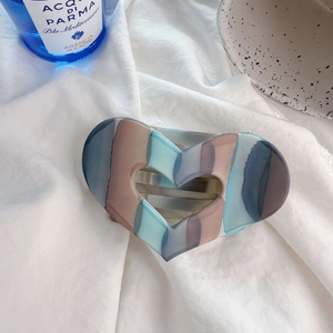 Dettaglio molletta per capelli a cuore con trama marmorizzata blu e marrone su tessuto