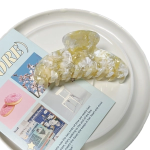 Pince à cheveux élégante en acétate motif marbre ambré sur une assiette blanche