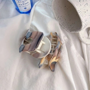 Dettaglio di fermagli per capelli in acetato opaco marmorizzato su tessuto bianco