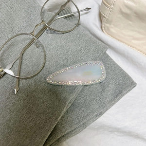 Close-up of pearl gloss hair clip with Born in France text and sparkling rhinestones