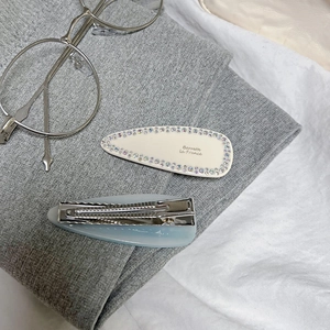 Macro shot of minimalist cream waterdrop clip with rhinestones and blue frosted hair clip