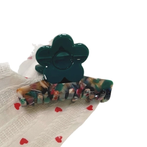 Green acetate flower hair claw clip with colorful marble texture and gold emblem detail